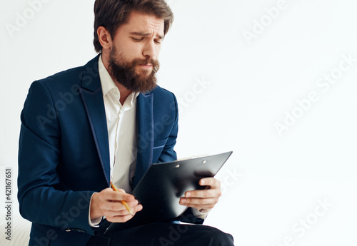 business man in a blue jacket and in a white shirt with documents in a folder on a light background
