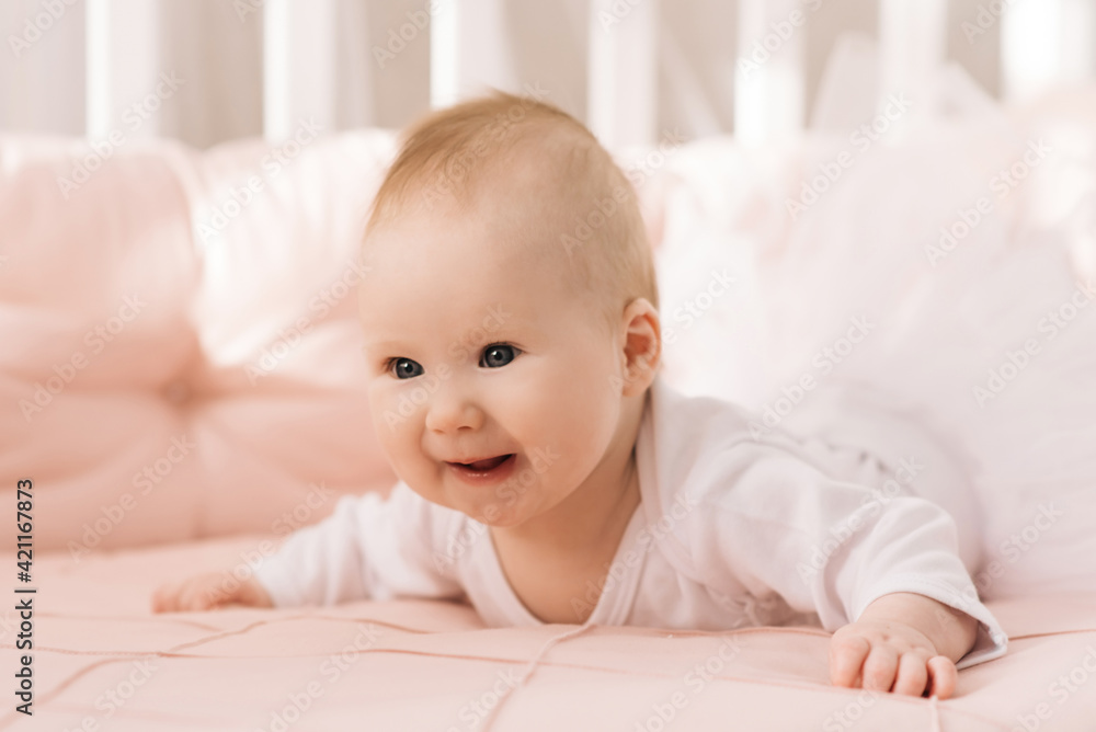 Portrait of a cute 6-month-old baby, a newborn girl lying in a baby crib Portrait of a cute 6-month-old baby, a newborn girl lying in a baby crib