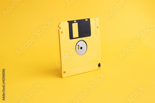 Yellow floppy disk on yellow background photo