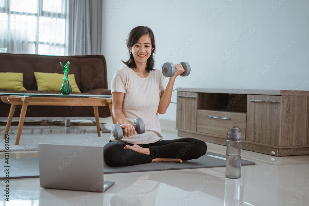 Young girl looking at laptop and doing exercises at home by her self Young girl looking at laptop and doing exercises at home by her self