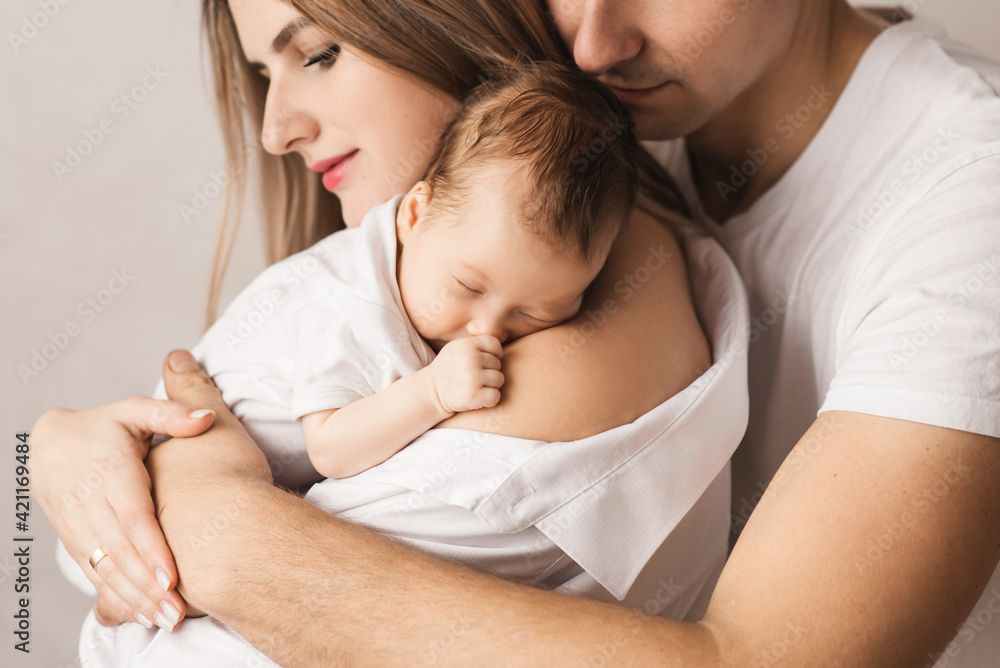 A loving mother carries her newborn baby at home. portrait of a happy mother holding a sleeping baby in her arms. Mother hugs her little 4-month-old daughter A loving mother carries her newborn baby at home. portrait of a happy mother holding a sleeping baby in her arms. Mother hugs her little 4-month-old daughter