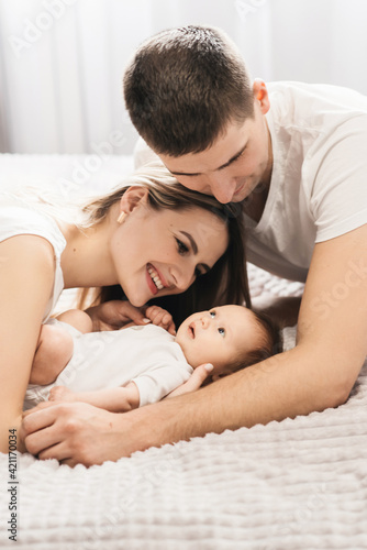 Woman and man holding a newborn. Mom  dad and baby. Close-up. Portrait of young smiling family with newborn on the hands. Happy family on a background.