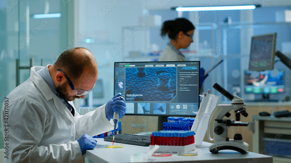 Man scientist using micropipette for filling test tubes in modern equipped laboratory. Team of researchers examining virus evolution using high tech for vaccine development against covid19 Man scientist using micropipette for filling test tubes in modern equipped laboratory. Team of researchers examining virus evolution using high tech for vaccine development against covid19