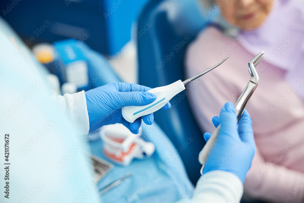 Dental male employee is demonstrating extraction instruments Dental male employee is demonstrating extraction instruments
