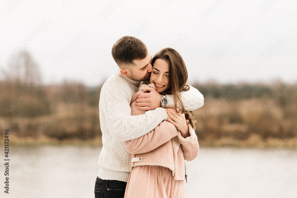 Young beautiful happy lovers man and woman, love story in winter with snow in a picturesque place