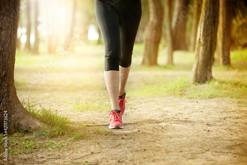 young woman legs jogging in the morning forest park wearing pink sneaker women and running leggings.