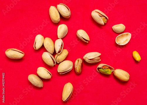 Close-up of fresh pistachio nuts on a red background.