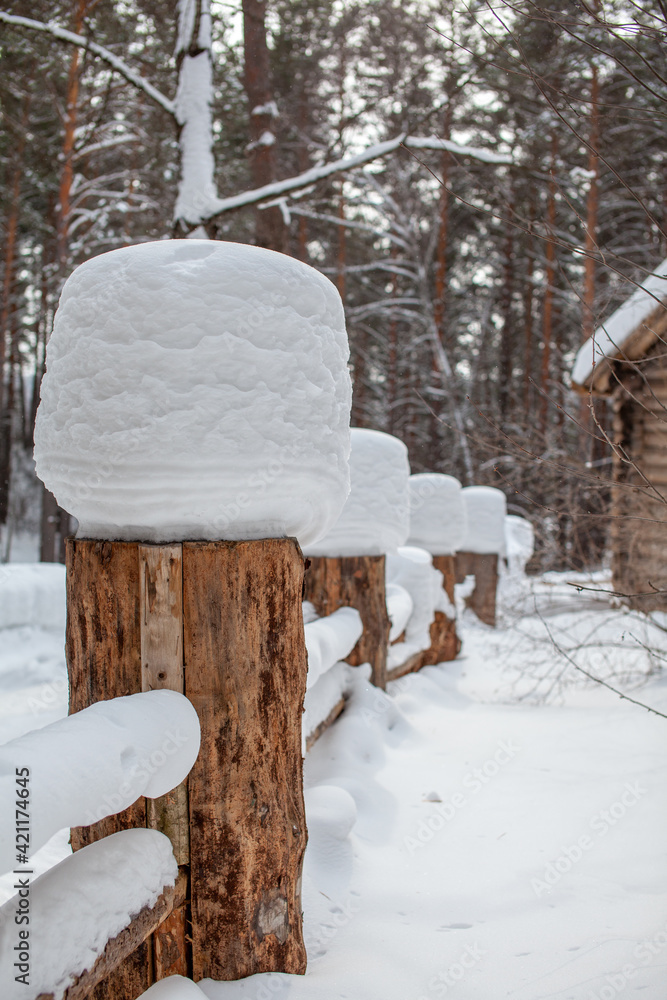 Large snow caps on the stumps of the fence in winter. Large snow caps on the stumps of the fence in winter.