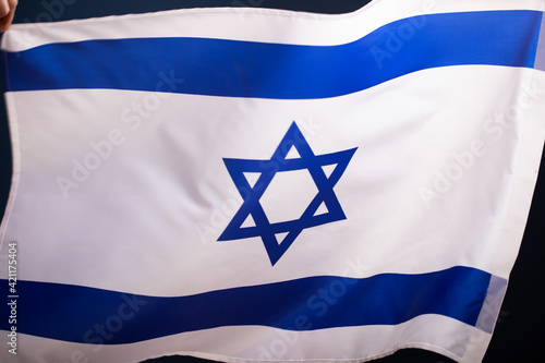 Israel flag waving against clean blue sky, close up.