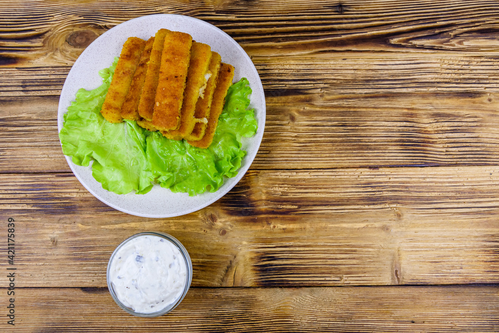 Baked fish sticks and lettuce leaves in a plate. Top view Baked fish sticks and lettuce leaves in a plate. Top view