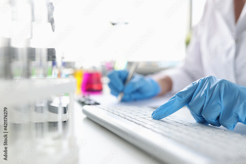 Scientist hands in gloves working on the keyboard at desktop Scientist hands in gloves working on the keyboard at desktop