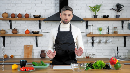 фотографія Man chef in black apron looking camera tells teaches housewife student records r
