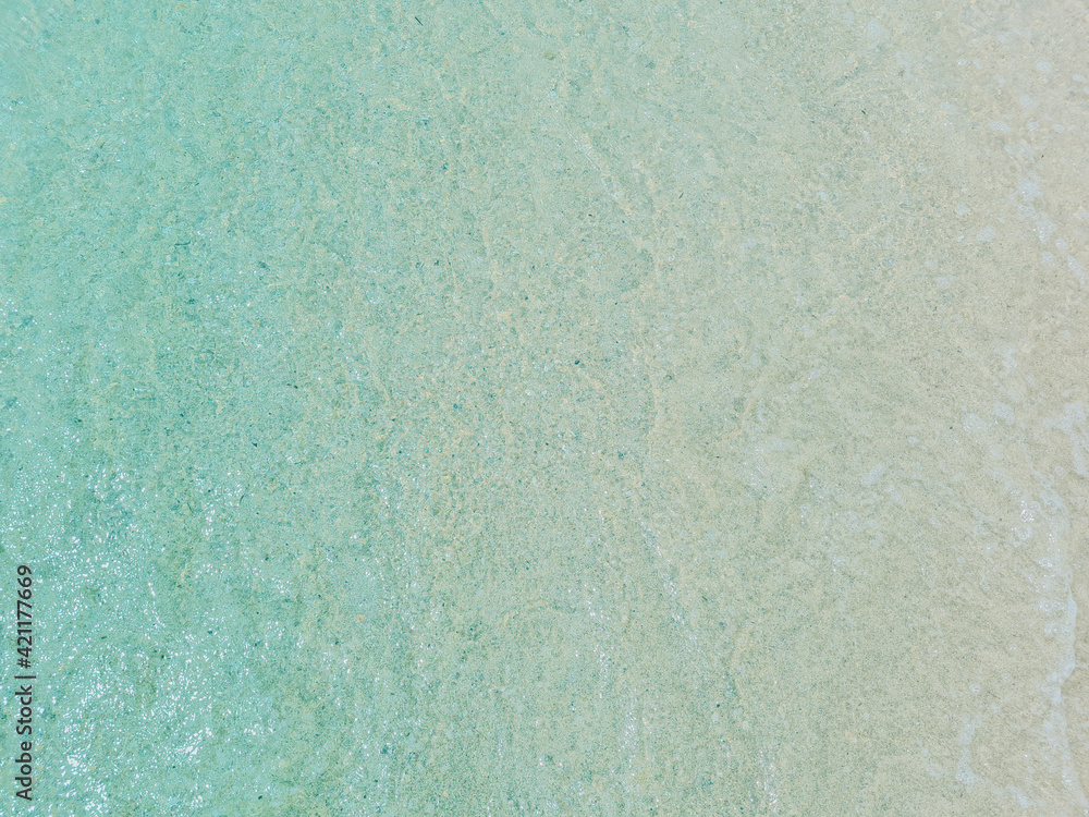 Light blue sea waves on a sandy beach background.