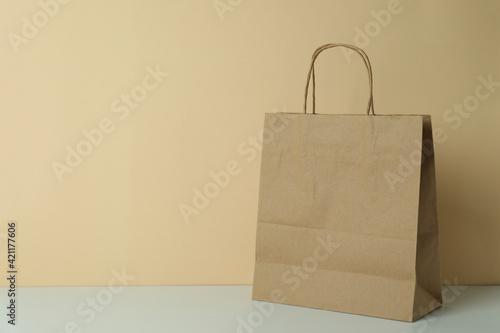 Blank paper bag on beige background, space for text