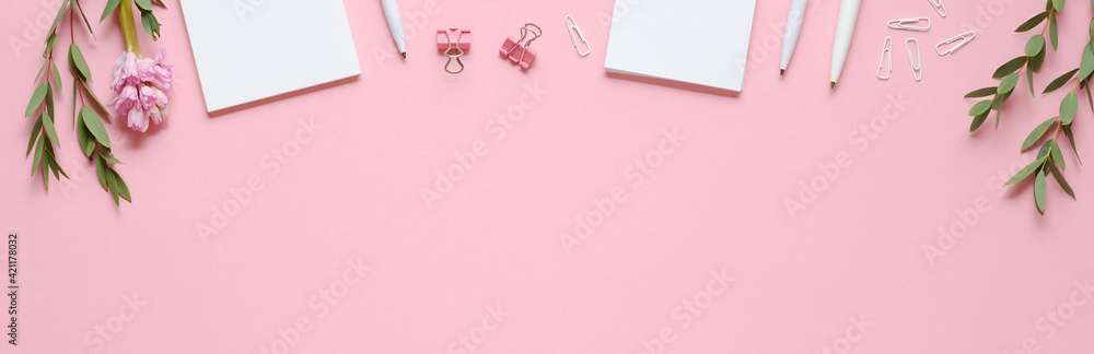 Workspace with notepad, pen, paper clips, eucalyptus and hyacinth on pink background