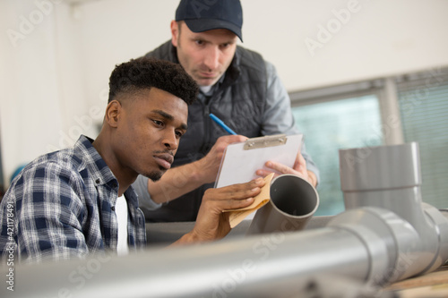 Fotografie supervisor assessing trainee assembling pipe fittings