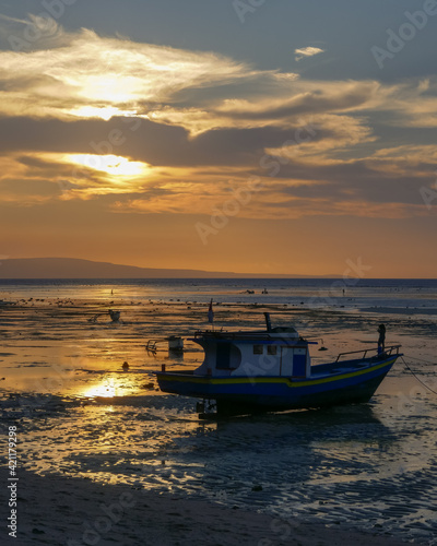 Colorful sunset view with fishing boat on the Sawu sea at Walakiri beach near Waingapu on Sumba island, East Nusa Tenggara, Indonesia