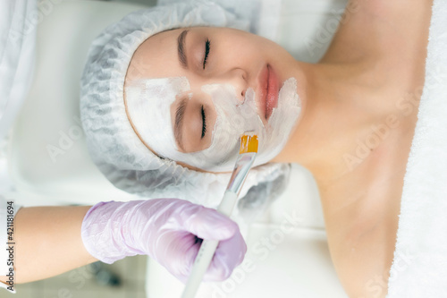 Facial skin care and protection. A young woman at a beauticians appointment. The specialist applies a cream mask to the face