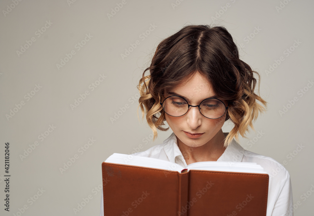 Business woman with open notebook in her hands and glasses on her face, white shirt Business woman with open notebook in her hands and glasses on her face, white shirt