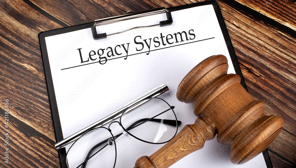 Paper with Legacy Systems with gavel, pen and glasses on the wooden background Paper with Legacy Systems with gavel, pen and glasses on the wooden background
