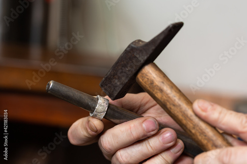 Obraz na plátne foreground, hammer hammering a silver ring to shape it in a jewelry workshop