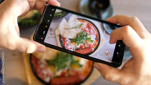 Taking Mobile Photo of Shakshuka Poached Eggs with Tomato and Bread Served in a Frying Pan. Israeli Arab Middle Eastern Cuisine. Top View. 4k