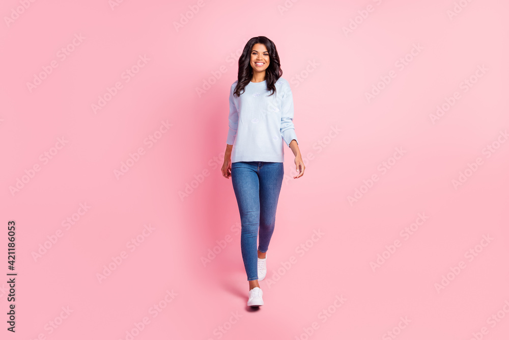 Photo of charming young lady walk look camera wear blue pullover jeans footwear isolated pink background Photo of charming young lady walk look camera wear blue pullover jeans footwear isolated pink background