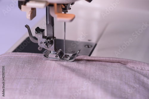 The light fabric lies on the sewing machine. The sewing process. Selective focus.