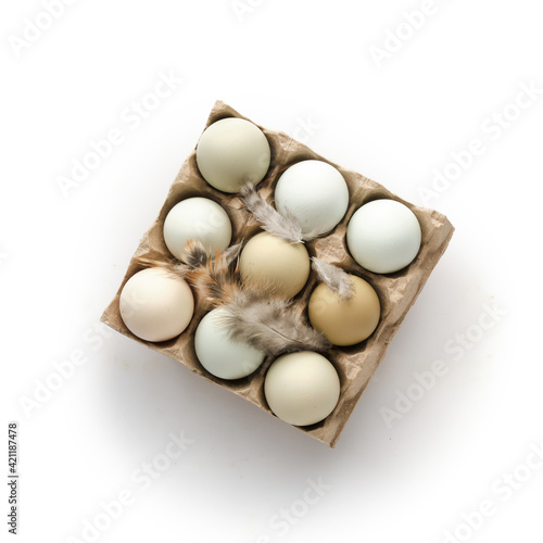 Fresh chicken eggs on white background. Multicolored eggs in craft carton pack isolated on white. Top view. Natural healthy food and organic farming concept
