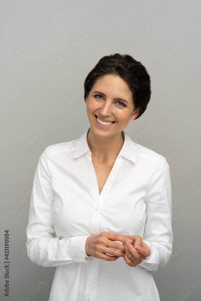 Shy smiling employee or business woman with perfect teeth smile, isolated on studio grey background. Portrait of happy cute modest dreamy office girl looking at camera, shy of praise. Shy smiling employee or business woman with perfect teeth smile, isolated on studio grey background. Portrait of happy cute modest dreamy office girl looking at camera, shy of praise.