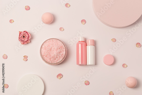 Rose scented sea salt in jar with small bottles shower gel, soap and rose flowers on round podium. Cosmetic product top view