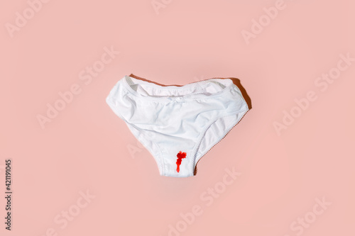White cotton panties for women with traces of fresh red blood. Concept of menstruation, female shame, taboo, daily hygiene, critical days, premenstrual syndrome