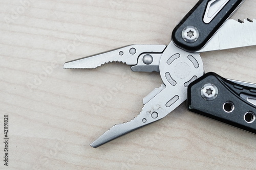 Selective focus of combination pliers on top light wooded color background. 