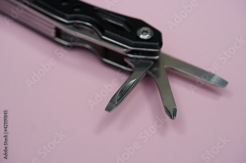 Unfolded pocket tool on pink background, selective focus. 