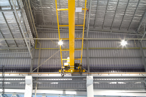 Overhead crane inside factory or warehouse. That industrial machinery or lifting equipment consist of hoist, hook and wire rope traveling on beam girder structure. For manufacturing production plant. photo