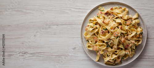 Photos Homemade Garlic Shrimp Bacon Alfredo on a plate on a white wooden background, top view