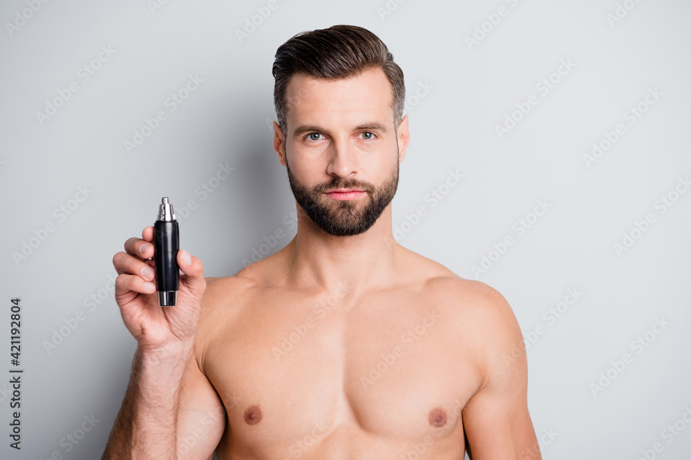 Photo of young handsome man serious hold hand electric hair cutter trimmer isolated over grey color background Photo of young handsome man serious hold hand electric hair cutter trimmer isolated over grey color background