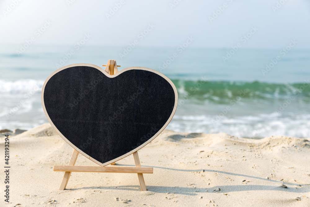 Chalkboard heart shape with a wooden frame Blank Chalk board  heart shape for write text, message or advertising, placed on the sand of a beach. Empty blackboard on sandy beach.