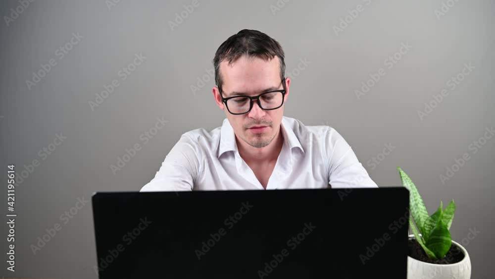 Young man in glasses works at the computer, front view