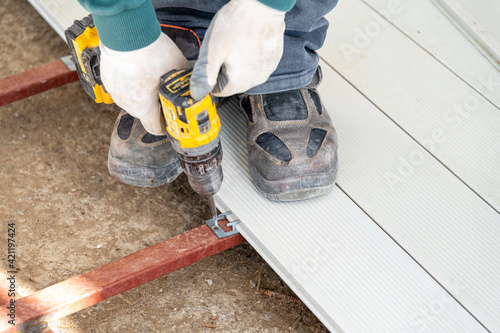 Man assembling composite deck using cordless screwdriver. photo