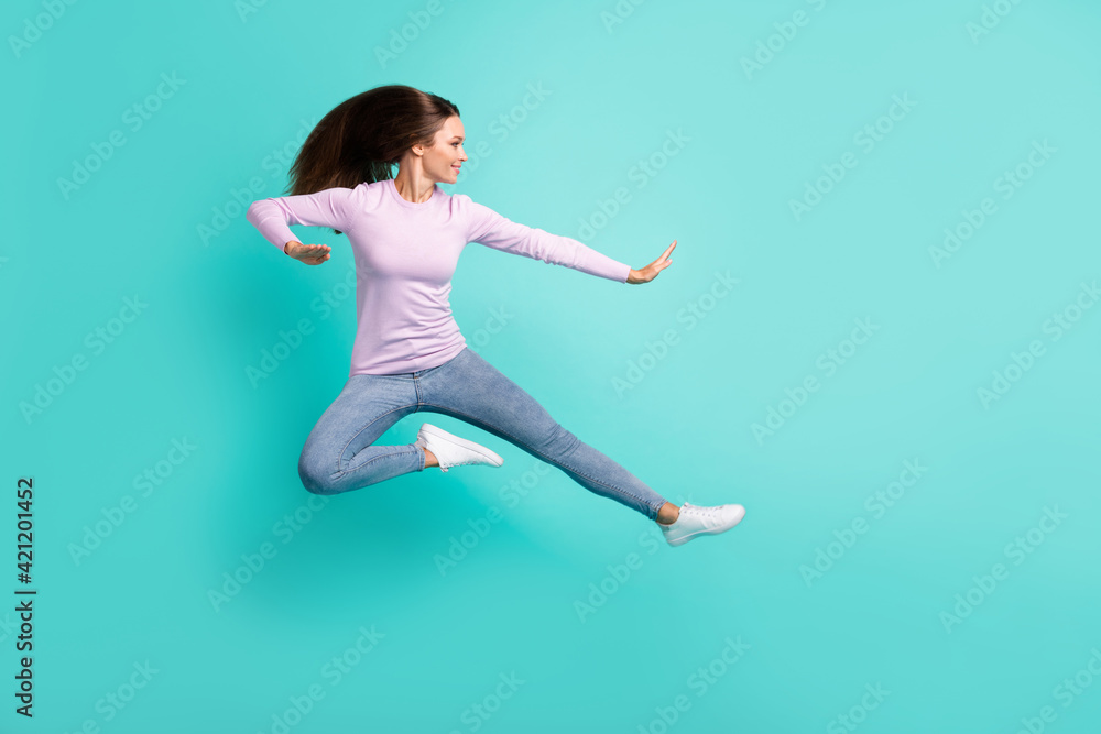 Full length body size view of attractive girl jumping fighting dancing having fun isolated over turquoise bright color background Full length body size view of attractive girl jumping fighting dancing having fun isolated over turquoise bright color background