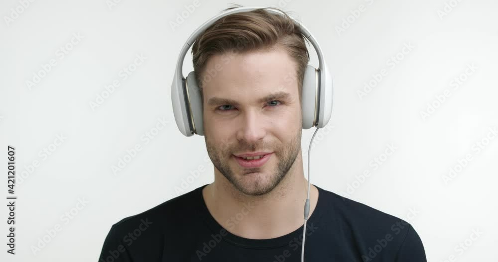 Attractive Caucasian Student wear Headphones looking Intently at the Camera. Looking Concentrated with cute Smile listening to Music. Standing on White studio Background. Enjoys Playlist. Attractive Caucasian Student wear Headphones looking Intently at the Camera. Looking Concentrated with cute Smile listening to Music. Standing on White studio Background. Enjoys Playlist.