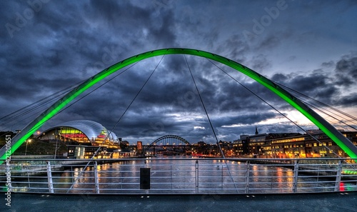 Gateshead Millenium Bridge in the foreground with the Sage and the Tyne Bridge in the background. The bridges connect Gateshead and Newcastle upon Tyne in northern England. photo