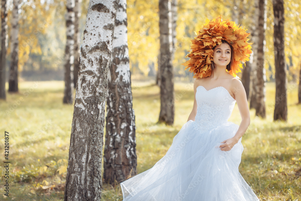 woman in white wedding dress with wreath of yellow autumn leaves