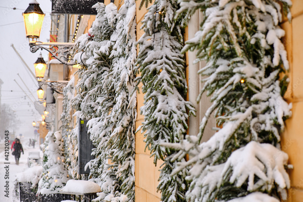 Aleksanterinkatu street during the strong snowstorm. Windows decorated with snow-covered spruce branches. The beautiful Christmas atmosphere in Helsinki, Finland.