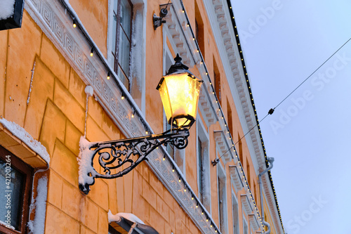 Obraz na płótnie The vintage street lamp on the building during the snowfall. The classic European architecture. w salonie