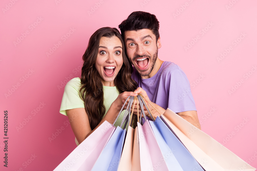 Portrait of attractive funny overjoyed trendy cheerful couple carrying new things black friday isolated on pink pastel color background Portrait of attractive funny overjoyed trendy cheerful couple carrying new things black friday isolated on pink pastel color background