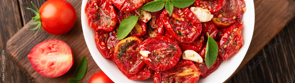 Top view of a bowl of sun-dried tomatoes in olive oil and with herbs banner panoramic