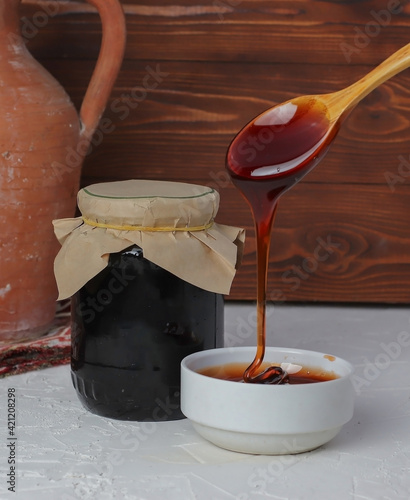 molasses in glass bowl and in wooden spoon 