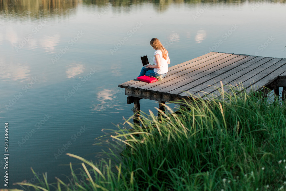 freelancer girl working with laptop outdoors near water